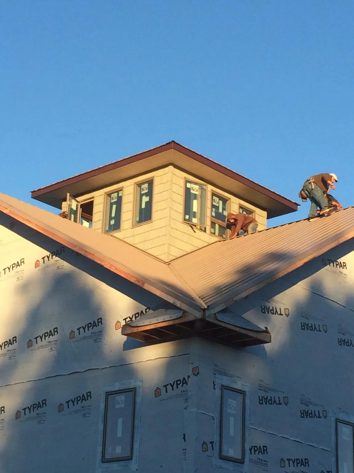 Roofers working around a rooftop cupola on a new metal roof at sunset — Roof Waterproofing in Gardiner by Roofing Brothers